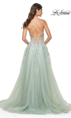 A woman wears the Sheer-Waist Long A-Line Prom Dress (La Femme 32438), a floor-length light green gown with delicate floral embroidery, an open crisscross lace-up back, tulle skirt, and elegant sheer waist detail.