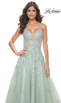 A woman in the Sheer-Waist Long A-Line Prom Dress (La Femme 32438)—a light green, sleeveless, embroidered lace gown with a deep V-neckline—stands before a white background. The La Femme logo is shown in the top right corner.
