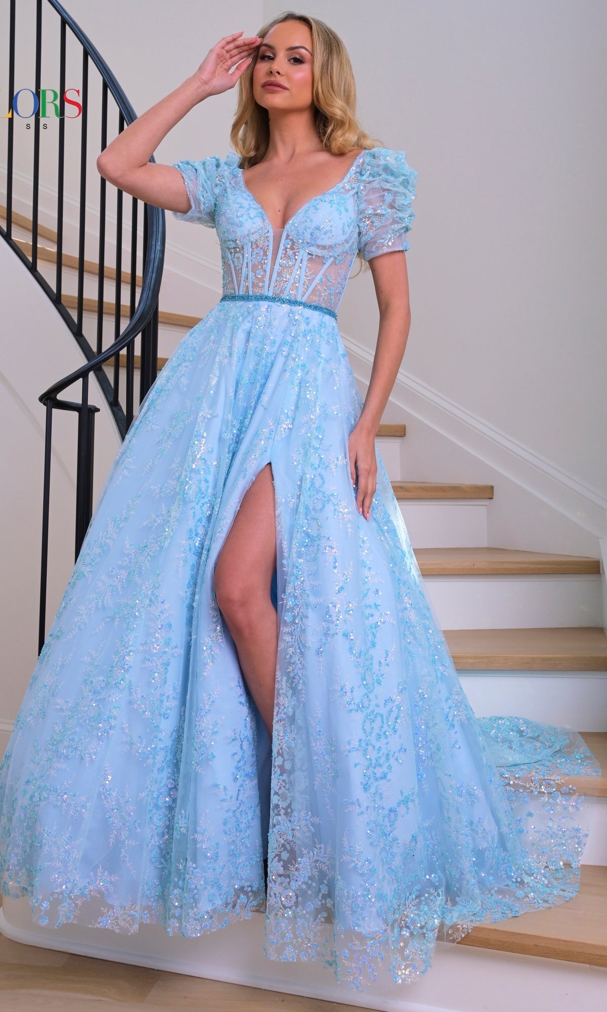 A woman in the Short-Sleeve Long Glitter A-Line Prom Dress 3243, featuring light blue sparkly fabric and a high slit, stands on a staircase with one hand near her forehead.