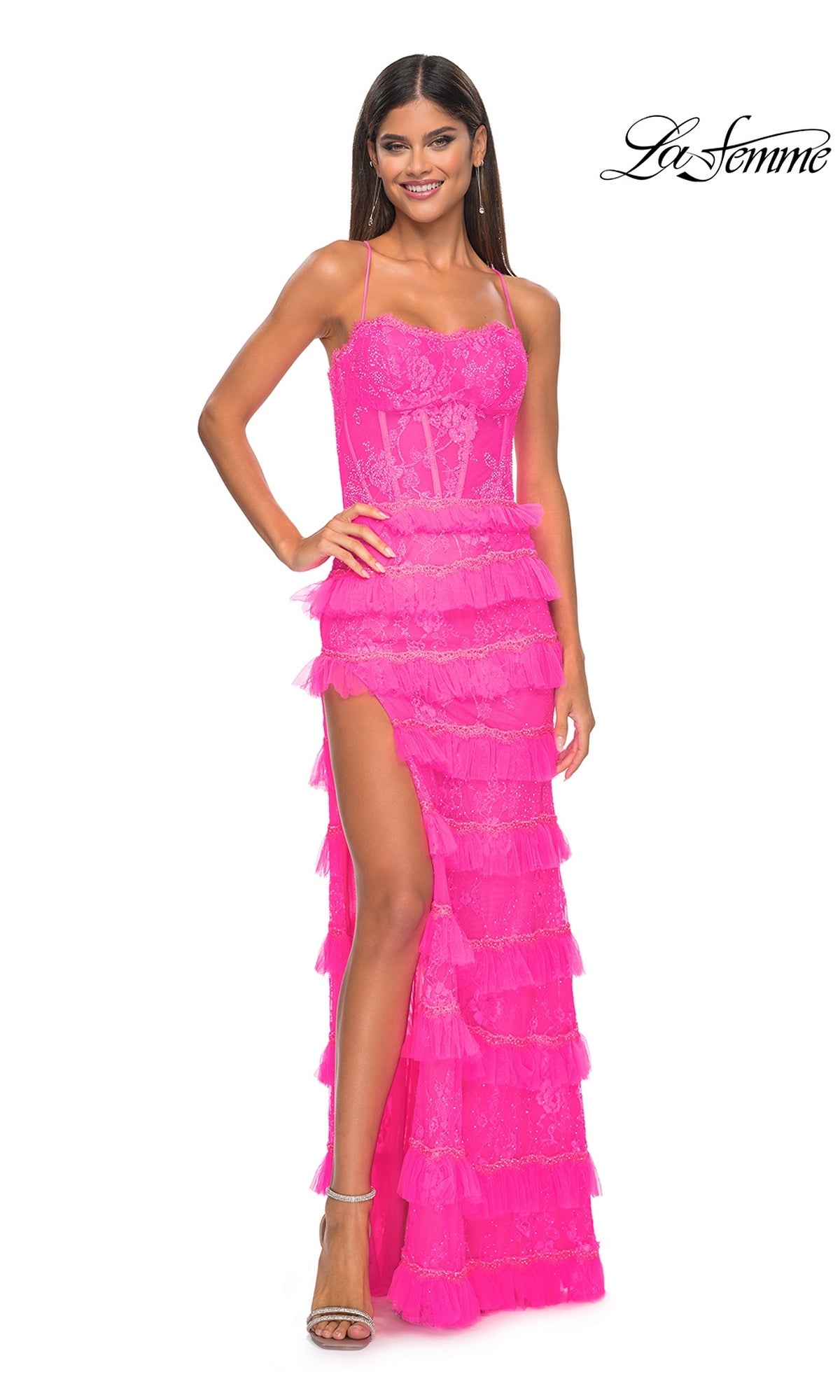 A woman stands smiling in the Ruffled Long Beaded-Lace Prom Dress: La Femme 32442, a bright pink gown with ruffles, spaghetti straps, a high slit, and beaded-lace detail. The 