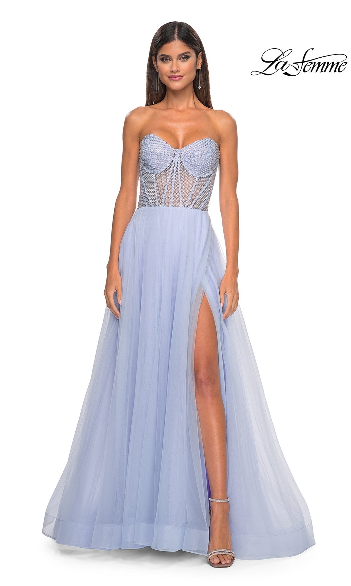 A woman wears the La Femme 32445 strapless long A-line prom dress in light periwinkle, featuring a sheer corset-style bodice and high slit, standing against a white background.