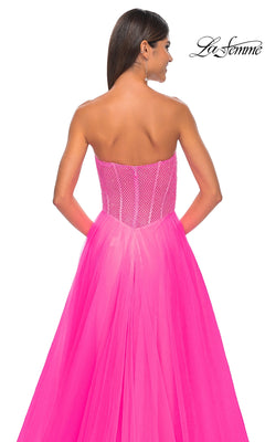 Woman wears the La Femme 32445 Strapless Long A-Line Prom Dress—bright pink with a fitted corset bodice, mesh details, and a flowing skirt—shown from the back against a white background.