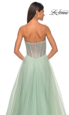 A woman faces away, showcasing the La Femme 32445 strapless long A-line prom dress in pale green with a sheer corset bodice and flowing tulle skirt. The "La Femme" logo appears top right, highlighting this elegant formal designer gown.