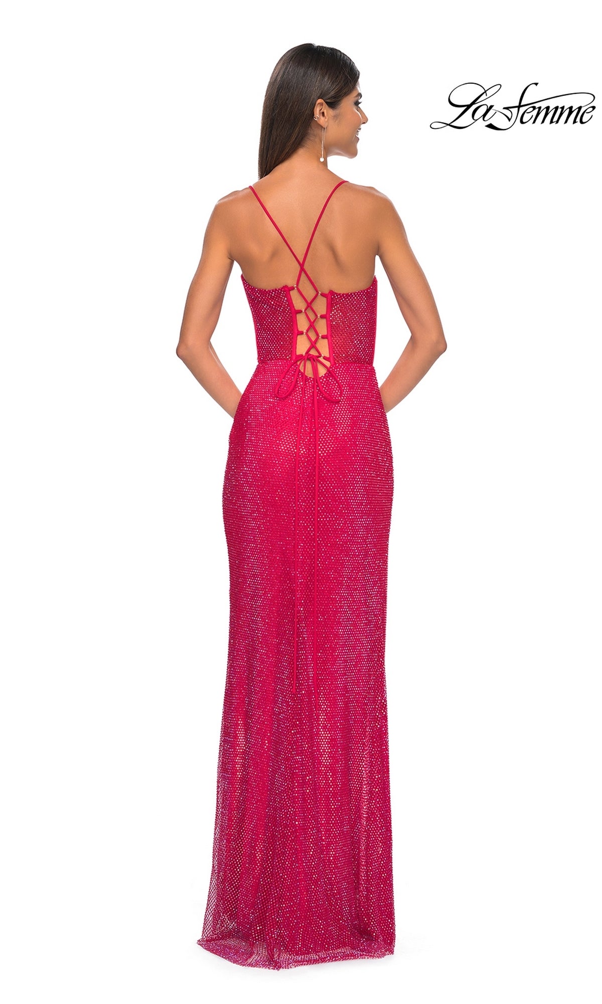Woman in a fitted, sparkling red Sheer-Bodice Long La Femme Fishnet Prom Gown 32446 with thin straps, corset-style bodice, and lace-up back detail, standing facing away from the camera.