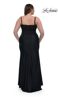 A woman models the Plus-Size Long Corset Prom Dress La Femme 32449, standing with her back to highlight the fitted bodice and flowing skirt of this elegant black formal gown.