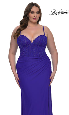 A woman models the Plus-Size Long Corset Prom Dress, La Femme 32449, in royal blue with a lace bodice and draped skirt, standing against a white background. The "La Femme" logo is shown in the top right corner.