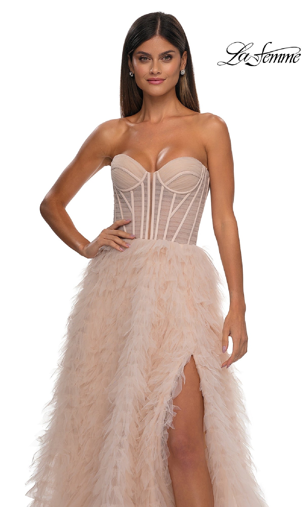 A woman stands against a plain white background wearing the La Femme 32528 Strapless Ruffled Prom Ball Gown, a long dress with a corset-style bodice, sheer accents, feathered skirt, and thigh-high slit. 