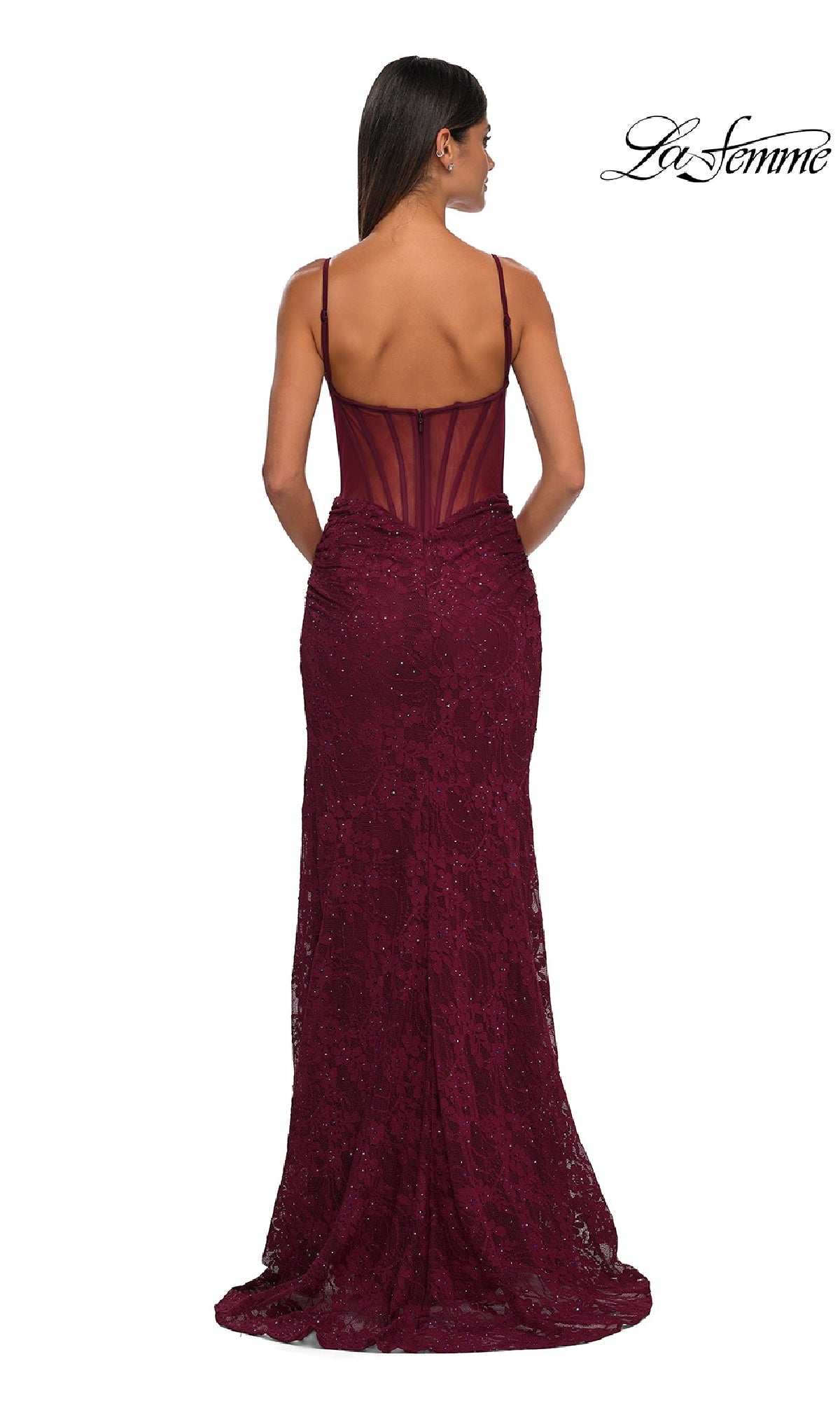 A woman stands with her back to the camera in a sleeveless, floor-length La Femme 32529 Sheer-Sides Long Beaded Prom Dress featuring thin straps and a sheer back panel.