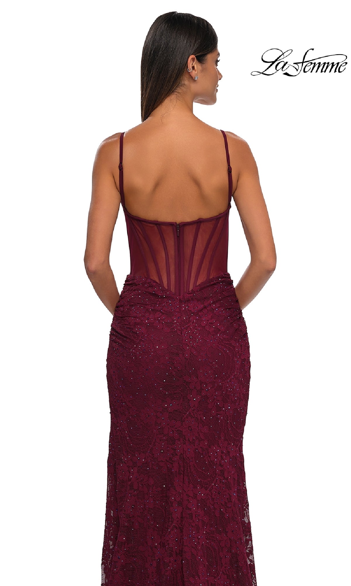 Woman in the Sheer-Sides Long Beaded Prom Dress (La Femme 32529), a sleeveless, fitted burgundy gown with thin straps and a sheer back panel, stands facing away. La Femme logo appears in the top right corner.