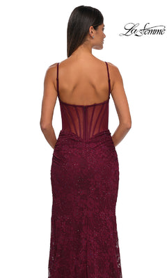 Woman in the Sheer-Sides Long Beaded Prom Dress (La Femme 32529), a sleeveless, fitted burgundy gown with thin straps and a sheer back panel, stands facing away. La Femme logo appears in the top right corner.