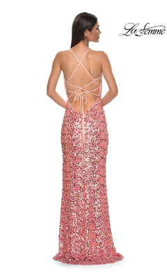 Woman models the La Femme 32550, a long pink prom dress with floor-length sequins, a high leg slit, and a strappy open back, standing with her back to the camera.