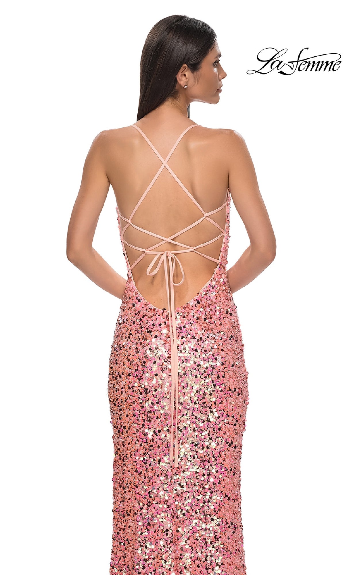 A woman stands with her back to the camera wearing the La Femme 32550 long pink sequin prom dress featuring a strappy open back, crisscross straps, and tie detail. The 