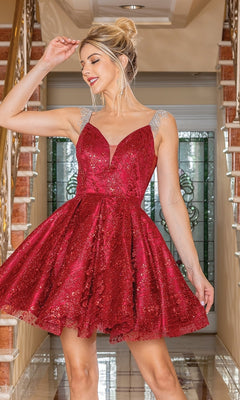 A woman in a Glitter Short Babydoll Homecoming Dress with silver straps stands indoors by a staircase, holding her dress and smiling.