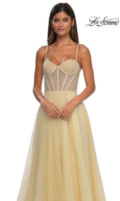A woman wears the Pearl Classic Long Prom Dress: La Femme 32644—a yellow gown with pearl beading, a sheer corset bodice, and thin straps—standing against a white background. The La Femme 32644 logo is in the top right corner.