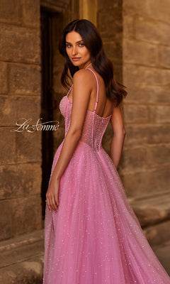 A woman poses in front of a stone wall, looking over her shoulder in the Pearl Classic Long Prom Dress: La Femme 32644, a strapless A-line gown featuring a fitted bodice and flowing skirt adorned with pearl beading.