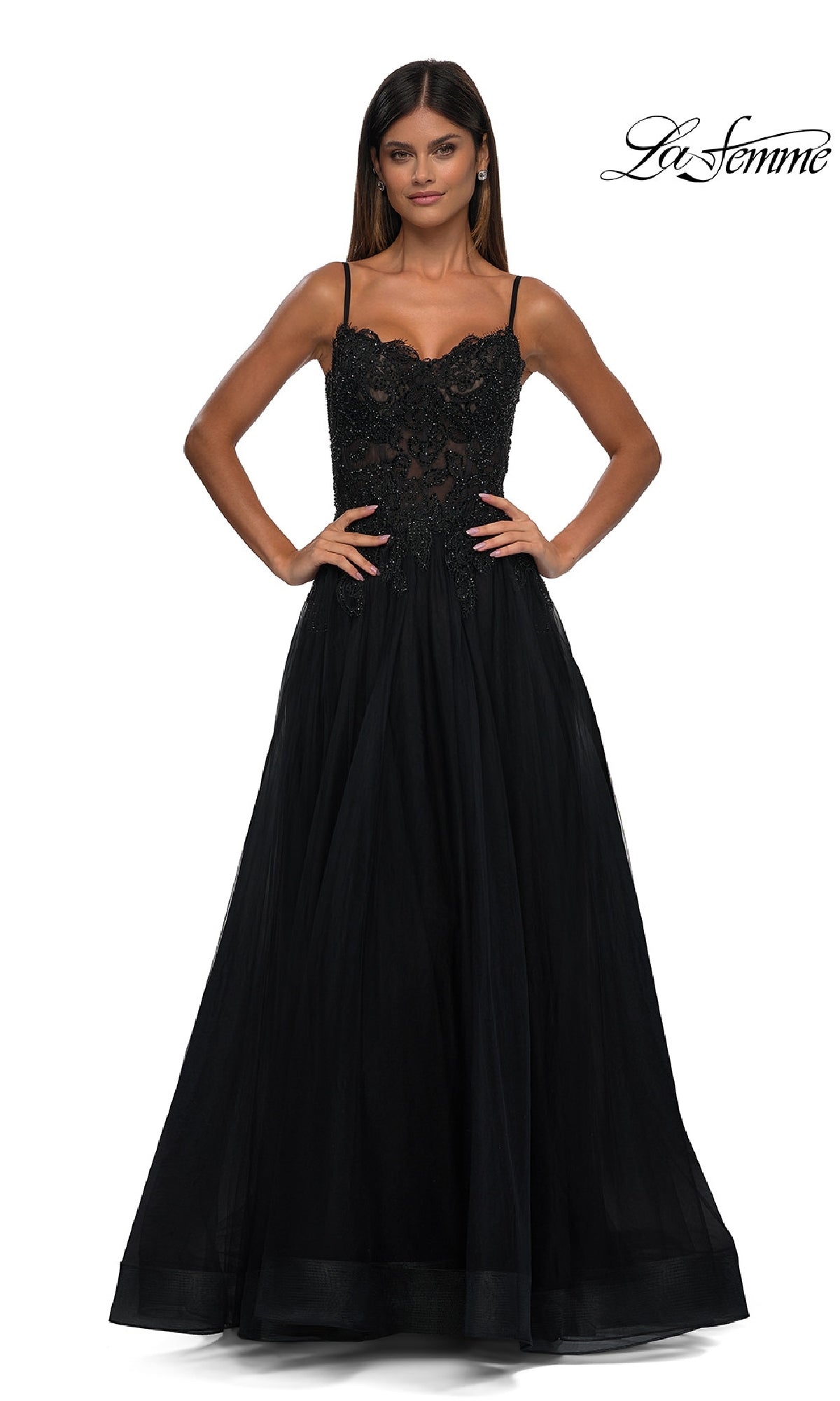 A woman stands facing forward in the Long Prom Ball Gown with Pockets: La Femme 32646, featuring a sleeveless black lace bodice and full tulle skirt, against a plain white background. The 