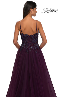 Woman in a dark purple La Femme 32646 long prom ball gown with pockets, thin straps, and beaded details, shown from the back against a white background.