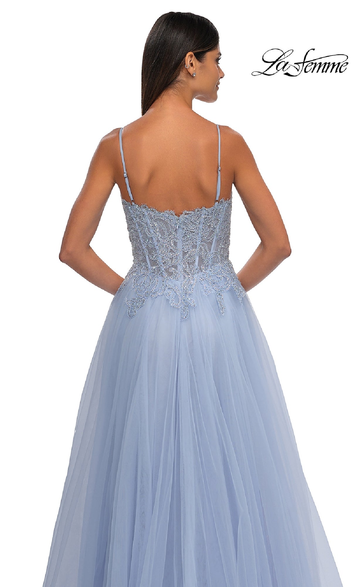 A woman faces away, wearing the La Femme 32646—a long blue prom ball gown with pockets, thin straps, lace details on a fitted bodice, and a flowing tulle A-line skirt.