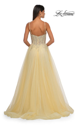 Woman in a yellow La Femme 32646 long prom ball gown with pockets, floor-length with thin straps and lace bodice detailing, shown from the back.