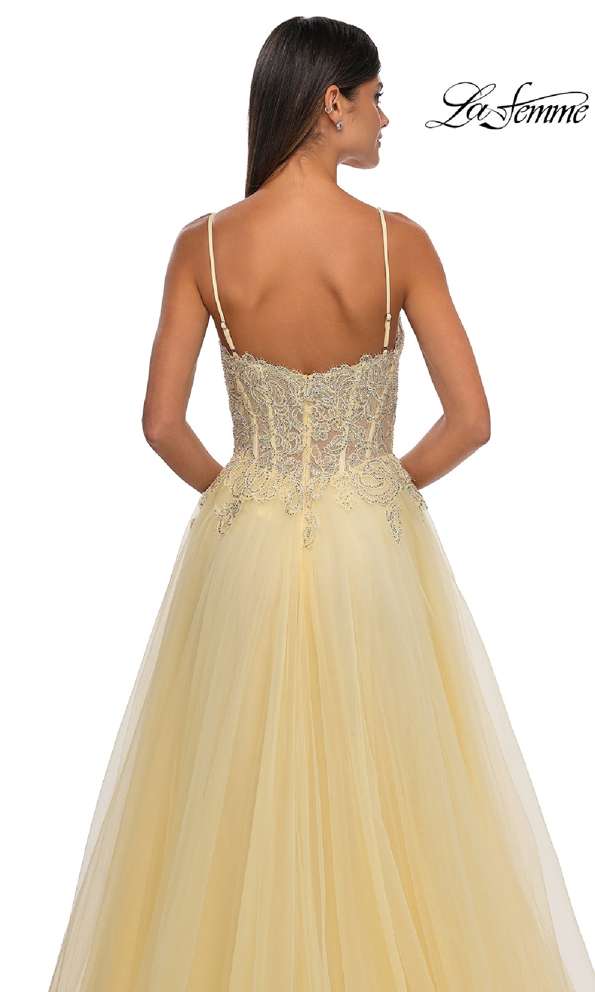A woman wears the Long Prom Ball Gown with Pockets: La Femme 32646 in pale yellow, featuring thin straps, an embroidered lace bodice, and a flowing tulle skirt. The La Femme logo appears in the top right corner of the image.