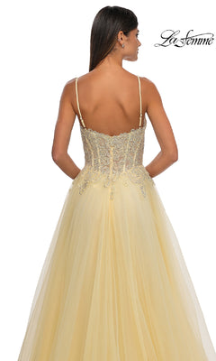 A woman wears the Long Prom Ball Gown with Pockets: La Femme 32646 in pale yellow, featuring thin straps, an embroidered lace bodice, and a flowing tulle skirt. The La Femme logo appears in the top right corner of the image.