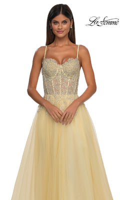 Woman wearing the La Femme 32646 Long Prom Ball Gown with Pockets, featuring a light yellow hue, lace-detailed fitted bodice, and thin straps, standing against a white background.