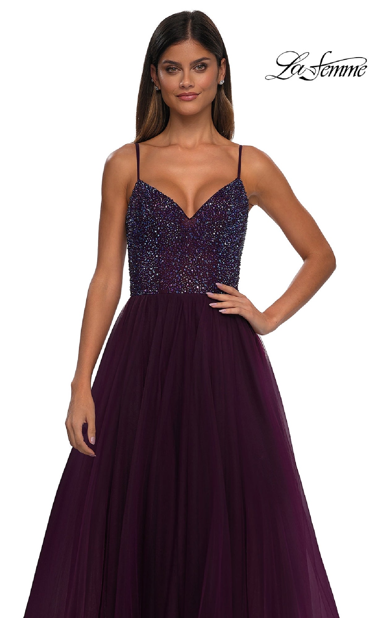 A woman wears the Beaded-Bodice Long Prom Ball Gown La Femme 32668, featuring a sleeveless dark purple a-line silhouette with a sparkly beaded v-neck bodice and tulle skirt, standing against a white background. 