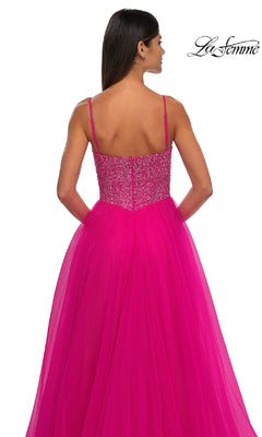 Woman in a bright pink La Femme 32668 prom ball gown with a beaded v-neck bodice and thin straps, shown from the back on a white background. "La Femme" logo appears in the top right corner.