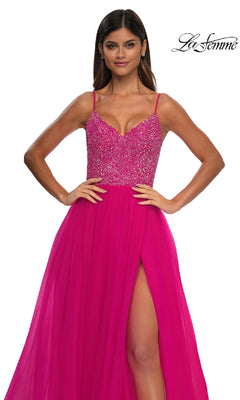 A woman stands with hands on hips in the Beaded-Bodice Long Prom Ball Gown (La Femme 32668), featuring a bright pink v-neck, beaded bodice, thin straps, and high slit against a white background. "La Femme" logo is in the top right corner.