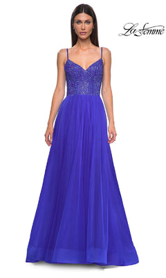 A woman wears the Beaded-Bodice Long Prom Ball Gown: La Femme 32668, a sleeveless royal blue a-line dress with a beaded v-neck bodice and tulle skirt, standing against a white background. The "La Femme" logo is in the top right corner.