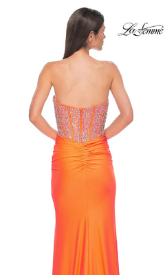 A woman is shown from the back wearing the Strapless Long Corset Prom Dress: La Femme 32669 in orange, featuring a beaded corset bodice and ruched jersey detailing, against a white background. The "La Femme" logo is in the top right corner.