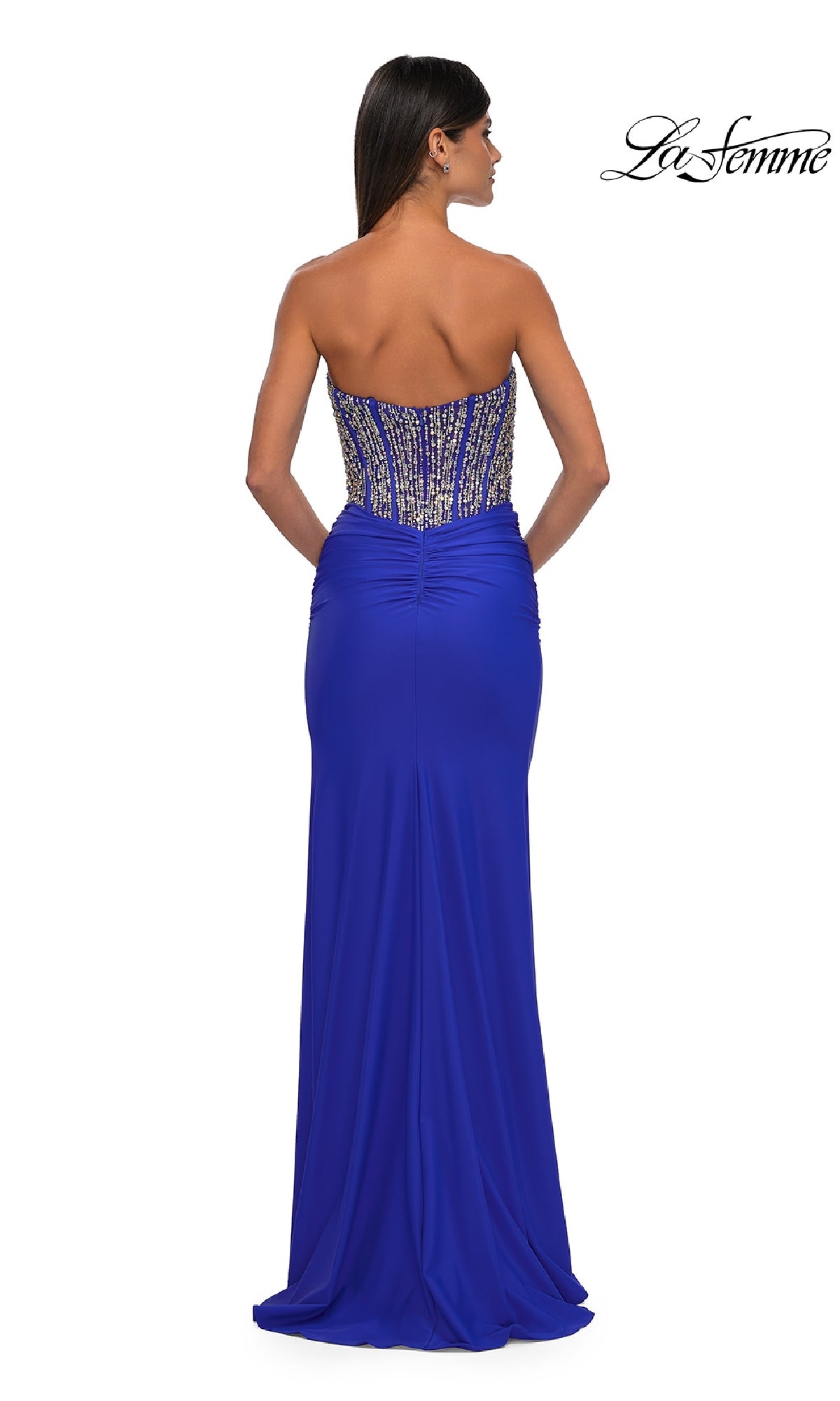 A woman elegantly showcases the La Femme 32669 strapless long corset prom dress in royal blue, featuring a beaded bodice and slight waist ruching, seen from the back.