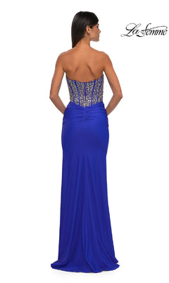 A woman elegantly showcases the La Femme 32669 strapless long corset prom dress in royal blue, featuring a beaded bodice and slight waist ruching, seen from the back.
