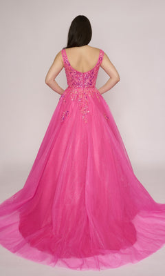 A woman facing away, wearing the Nina Canacci 3266 long prom dress in bright pink with floral embellishments and a sheer glitter tulle overlay.