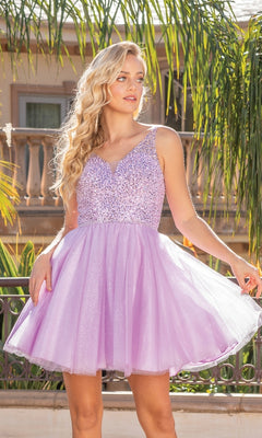 A woman stands outdoors in sunlight, wearing the Sleeveless Sequin-Bodice Short Glitter Prom Dress in light purple, its sparkling fabric catching the light against a backdrop of greenery and a building.