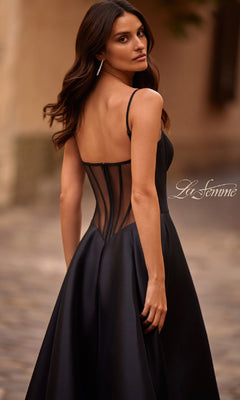 Woman in a La Femme 32670 Sheer-Corset Long A-Line Prom Gown, featuring a sheer back and crafted from stretch Mikado, standing outdoors and looking over her shoulder.
