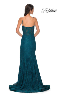 A woman stands with her back to the camera in the Beaded-Lace Long Corset Prom Dress: La Femme 32671, featuring teal lace, thin straps, and a train. The “La Femme” brand name appears in the top right corner.