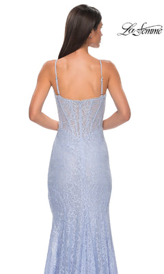 A woman is seen from the back wearing the Beaded-Lace Long Corset Prom Dress: La Femme 32671, a fitted light blue gown with spaghetti straps, a sheer corset-style bodice, and delicate lace details. The La Femme logo is visible in the image.