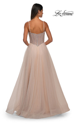 A woman is shown from the back wearing the Long Corset Prom Ball Gown: La Femme 32675—a floor-length blush a-line dress with a sheer corset bodice, spaghetti straps, and a full tulle skirt for an elegant look.