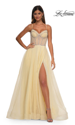 Woman models a pale yellow La Femme 32675 Long Corset Prom Ball Gown featuring a sheer structured bodice, spaghetti straps, and a high slit skirt. The elegant floor-length dress exudes timeless sophistication. La Femme logo appears top right.
