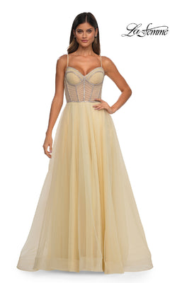A woman wears the La Femme 32675, a long yellow sheer tulle prom ball gown with thin straps and a structured corset bodice. The elegant A-line dress radiates timeless glamour. “La Femme” logo appears in the top right corner.