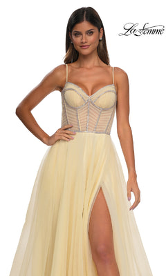 A woman models the La Femme 32675 Long Corset Prom Ball Gown: pale yellow, sleeveless A-line with thin straps, sheer corset bodice, silver accents, and a high slit. "La Femme" logo appears in the top right corner.