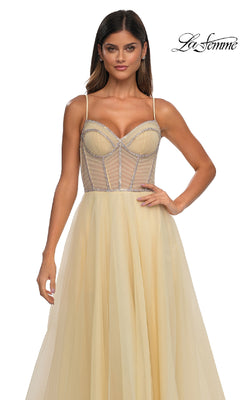 A woman poses against a white background wearing the La Femme 32675, a yellow tulle A-line prom ball gown featuring a sheer, structured corset bodice and thin straps.