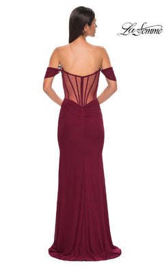 Woman wearing the Off-the-Shoulder Corset Prom Gown: La Femme 32684, a floor-length burgundy dress with a sheer back panel and ruched details. The elegant La Femme logo appears in the top right corner.