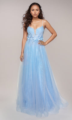 A woman stands facing forward in the Nina Canacci 3268, a long light blue formal A-line dress with spaghetti straps and 3D floral appliques at the waist, set against a plain light background.