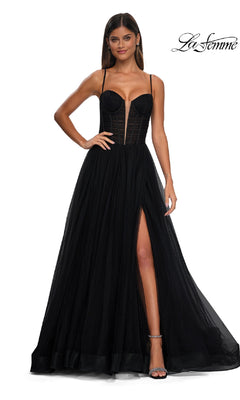 A woman in the La Femme 32700 Tulle Prom Ball Gown with pockets, featuring a floor-length a-line skirt, sheer corset bodice, high slit, and thin straps, poses against a white background.