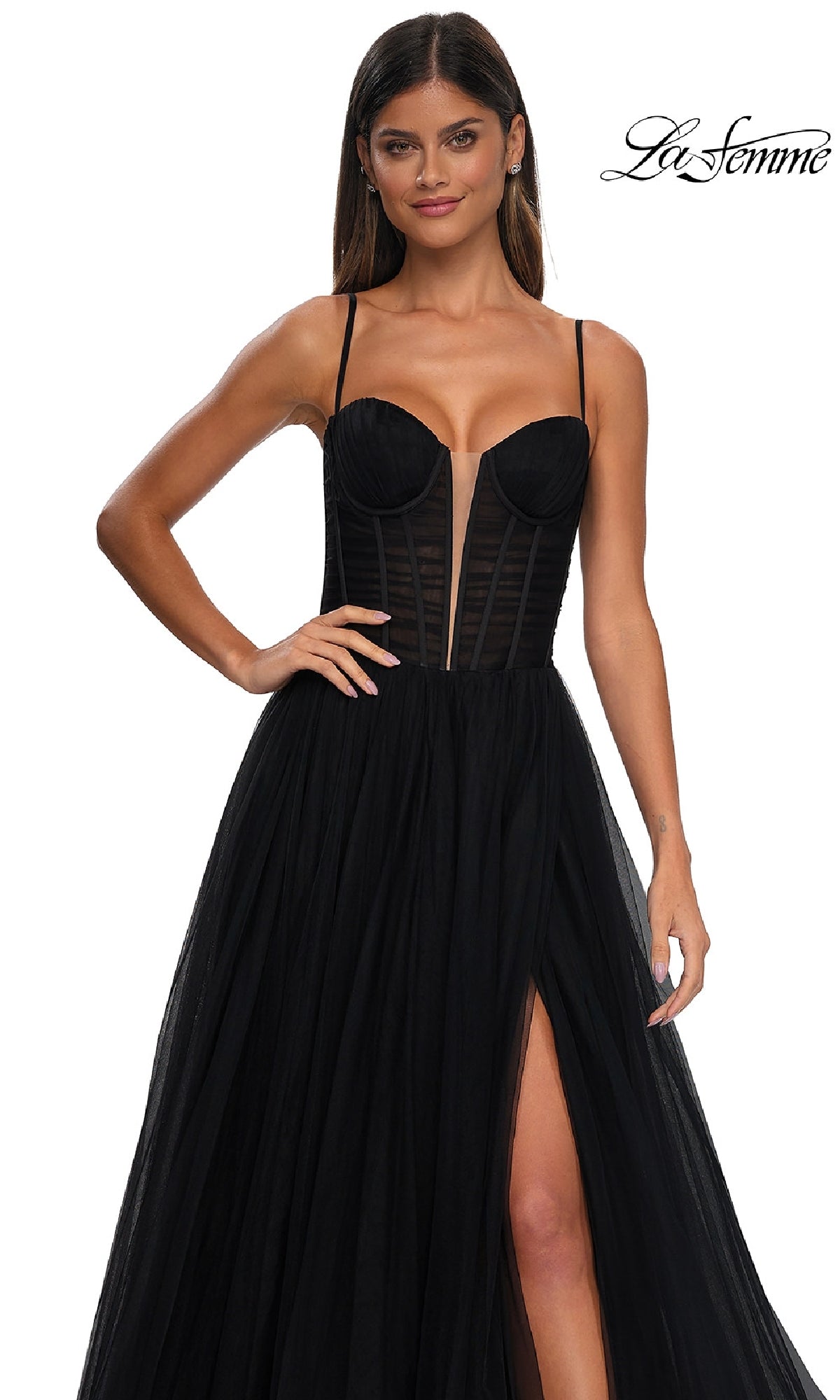 A woman stands against a plain white background wearing the La Femme 32700—a black tulle prom ball gown with pockets, featuring a strapless design, sheer corset bodice, thigh-high slit, delicate panels, and thin straps.