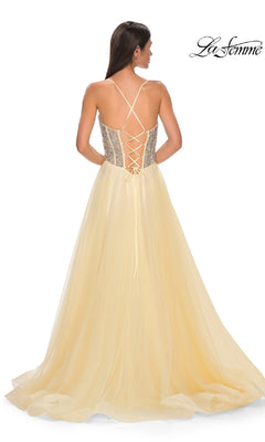 A woman faces away in the Beaded-Corset Long Prom Dress (La Femme 32703)—a sleeveless, floor-length pale yellow A-line gown with a lace-up back and tulle skirt. The "La Femme" logo appears in the top right of this elegant scene.