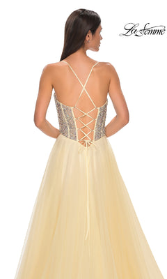 A woman in the La Femme 32703 Beaded-Corset Long Prom Dress, pale yellow with a rhinestone-beaded corset bodice, crisscross lace-up back, and flowing tulle skirt.