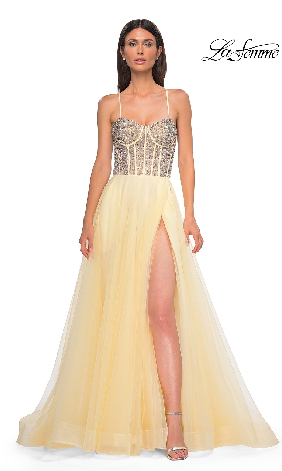 A woman models the Beaded-Corset Long Prom Dress: La Femme 32703, featuring a yellow rhinestone corset, sheer skirt, spaghetti straps, and high leg slit, standing against a white background.